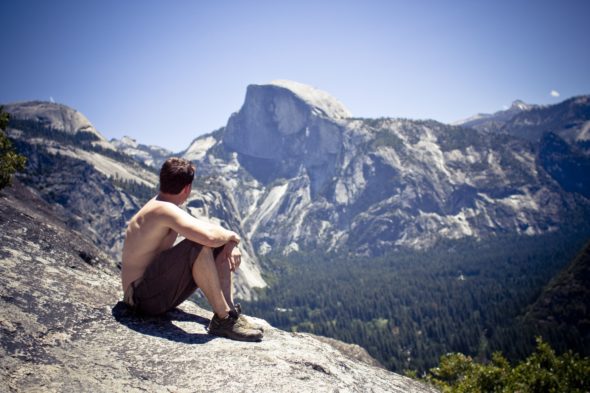 Author and filmmaker Tyler Dunning sitting on a rock looking at mountains in Yosemite