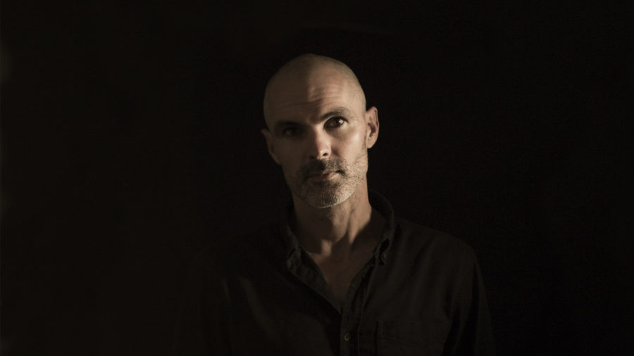 dramatic portrait of a white man wearing a black shirt against a black backdrop